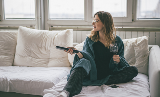 lady sitting on her couch watching tv and drinking wine