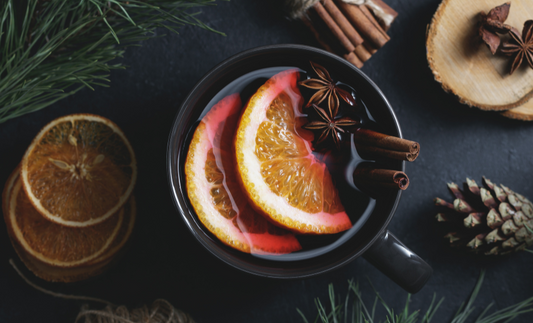 a mug of mulled wine with oranges and cinnamon sticks in it