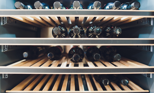 shelves of a wine fridge filled with bottles of wine