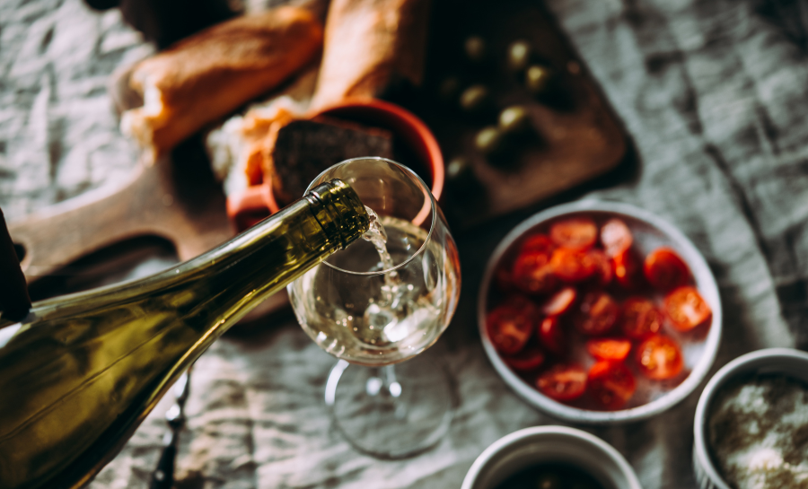 display of food with someone pouring white wine into a wine glass
