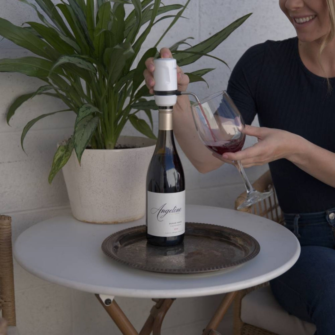 Lady using a white Aervana Travel wine aerator to aerate red wine into a wine glass