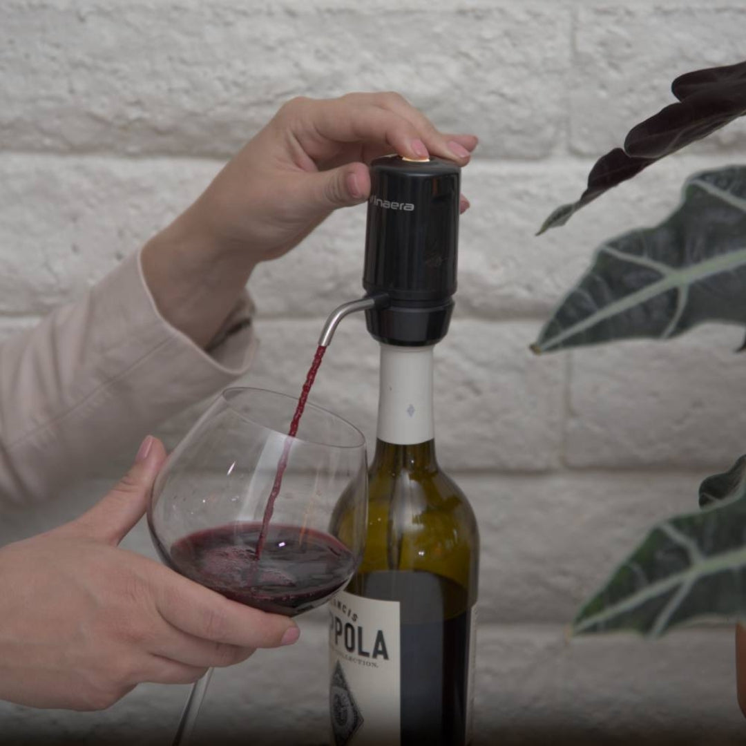 Lady using black Aervana Travel wine aerator to aerate red wine into her wine glass